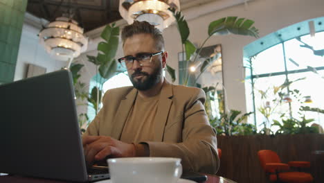 Caucasian-Businessman-Working-on-Laptop-in-Cafe